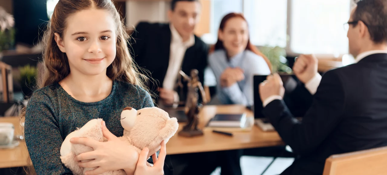 little girl holding teddy bear while parents are planning trusts